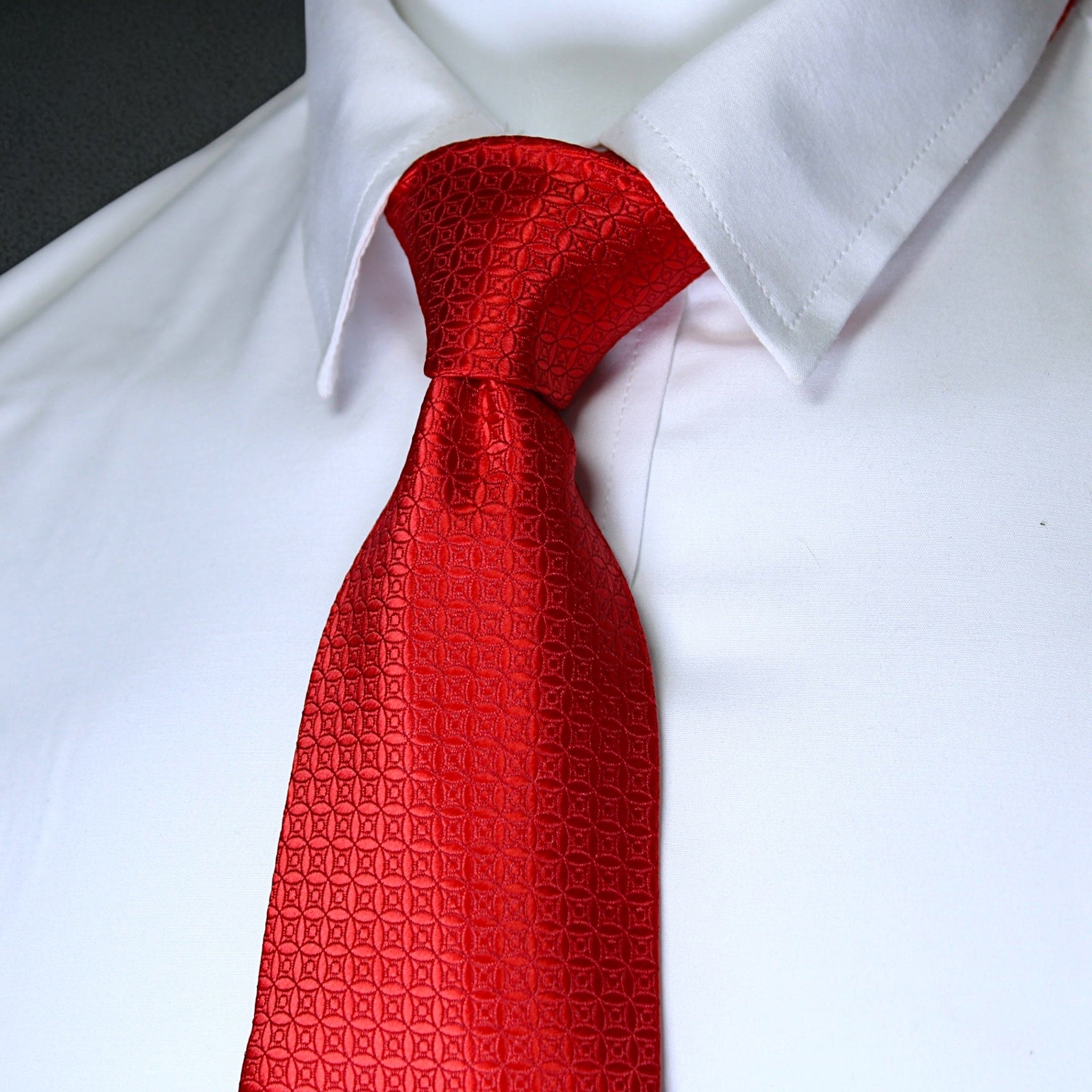 Red patterned tie on a white shirt against a neutral background