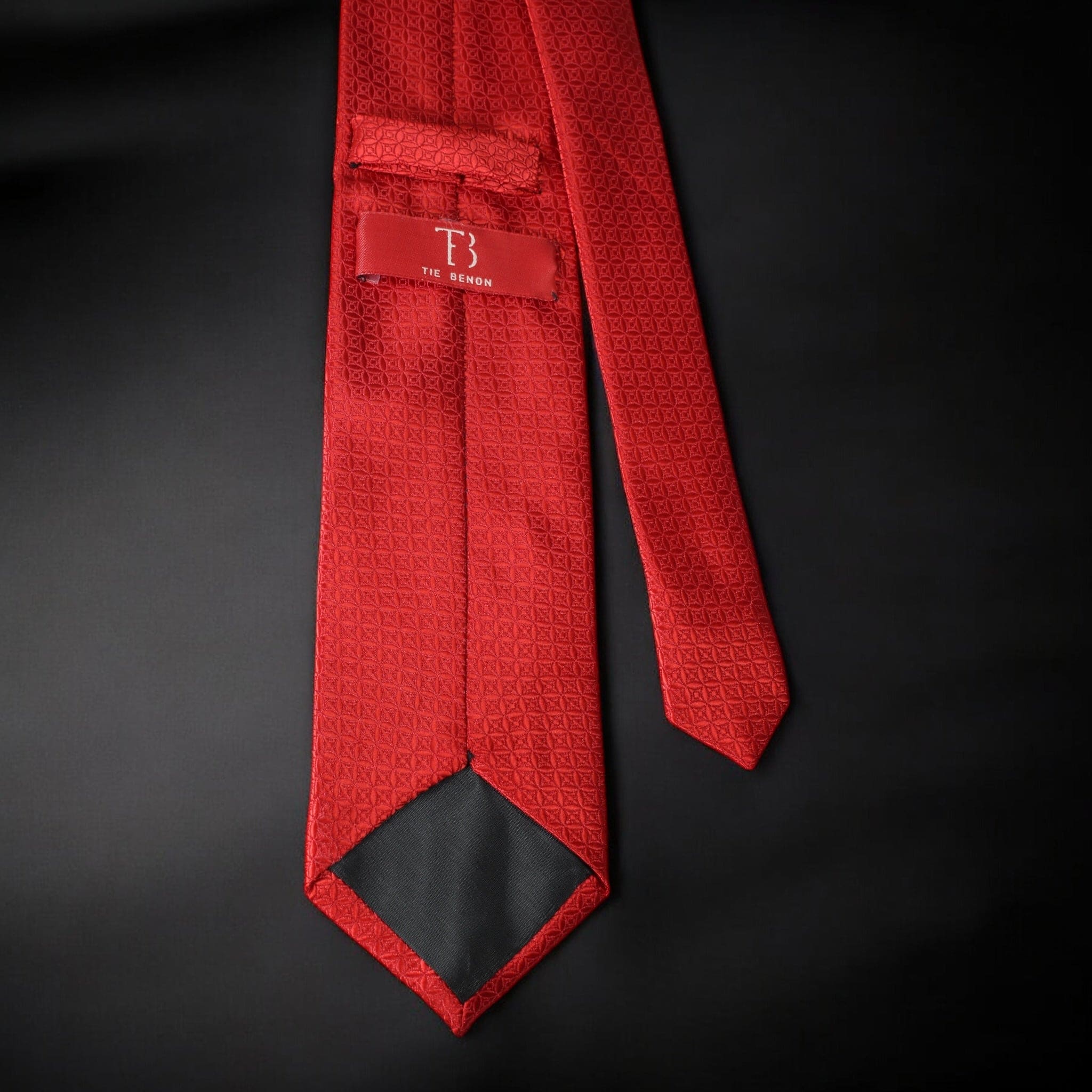 Red textured tie with a brand label on a black background