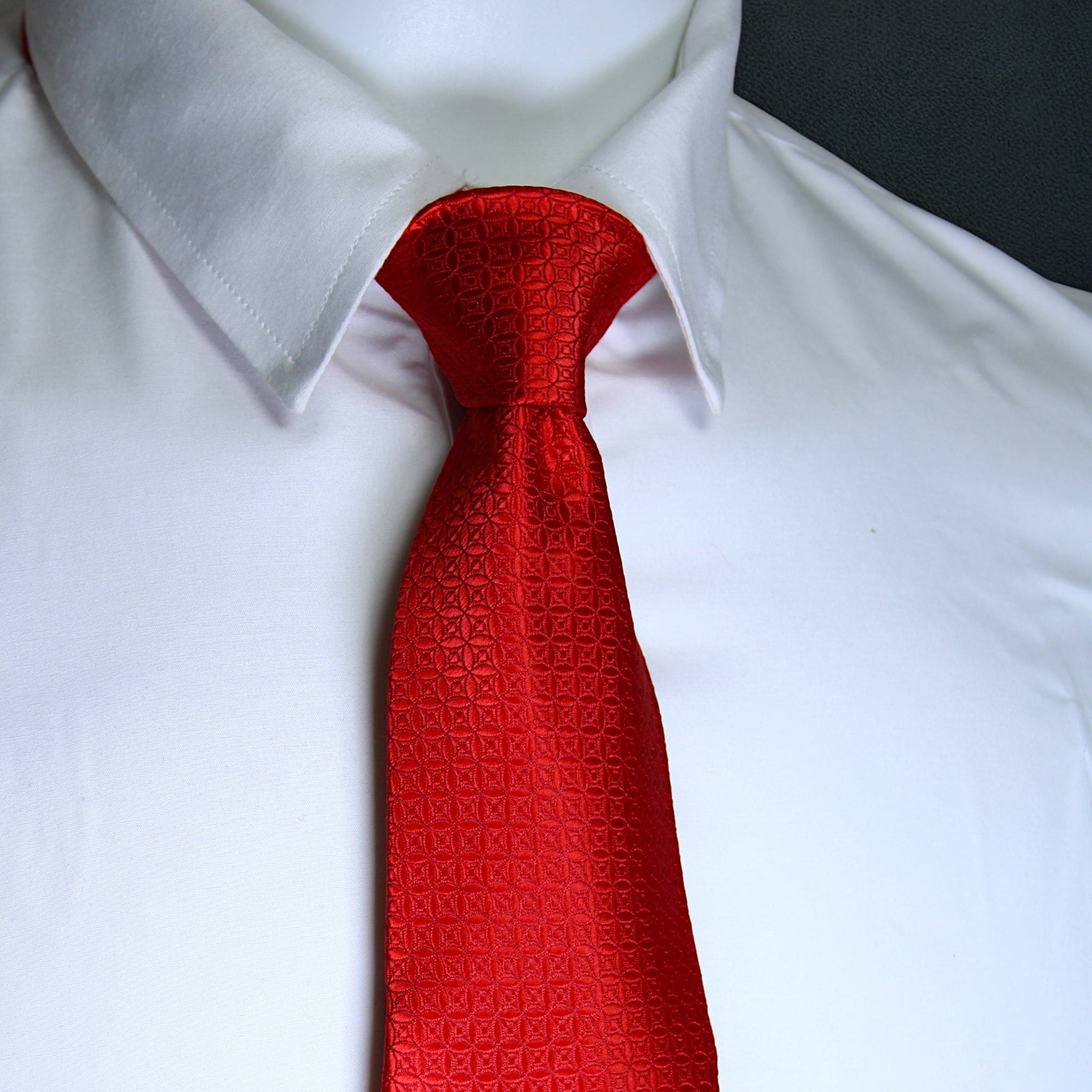 Red patterned tie on a white shirt with a blurred background