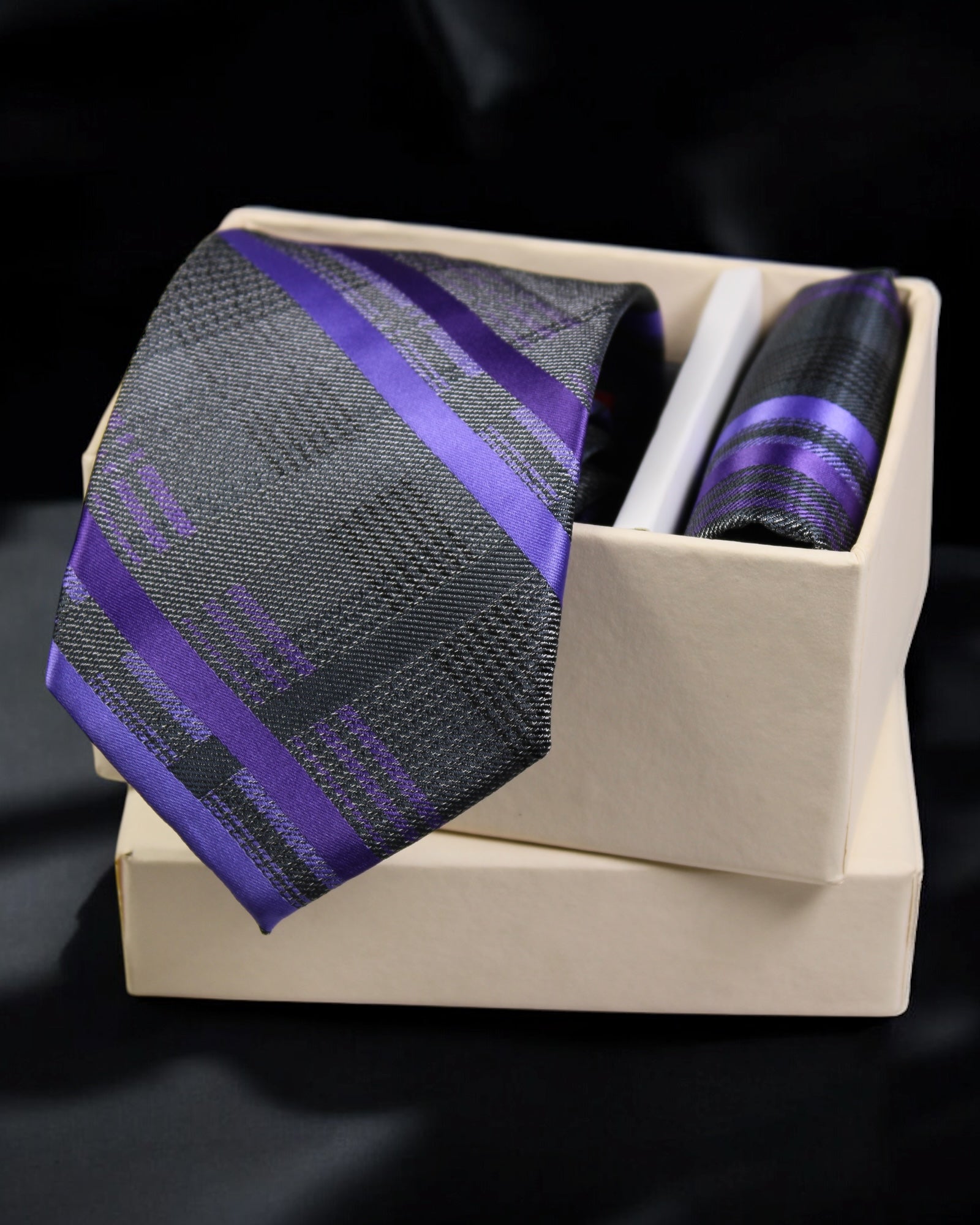 Black and purple striped tie in a beige box on a black background