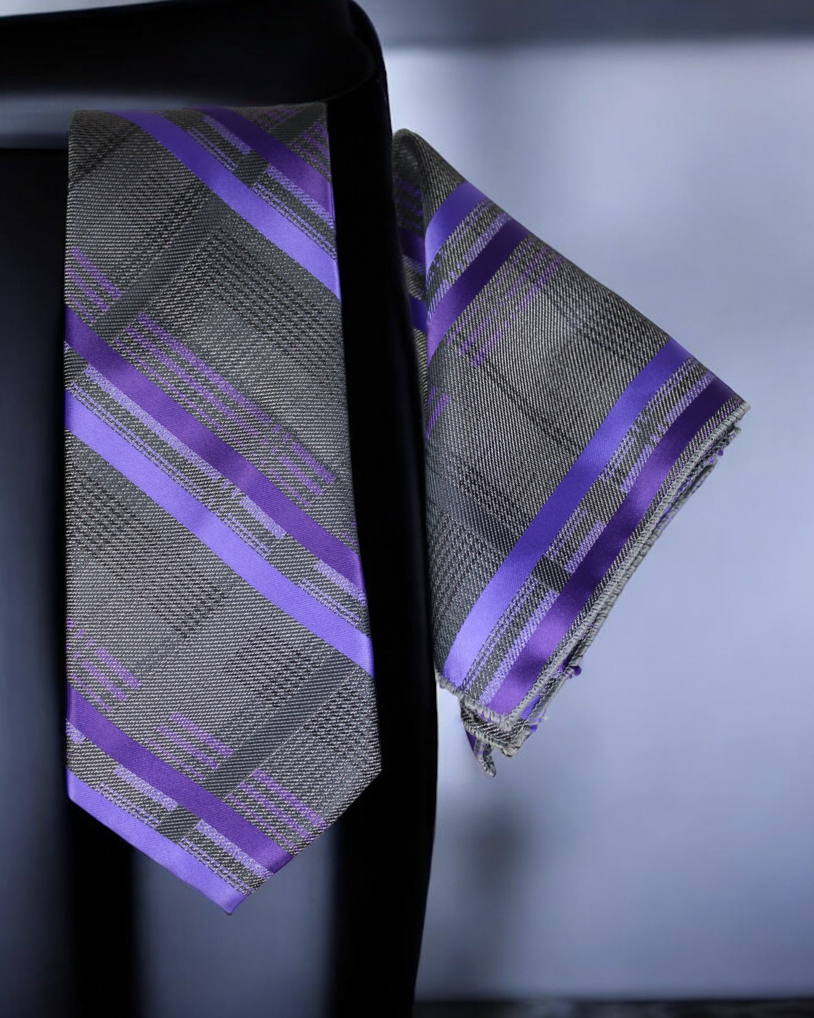 Gray and purple striped tie and pocket square set on a dark background