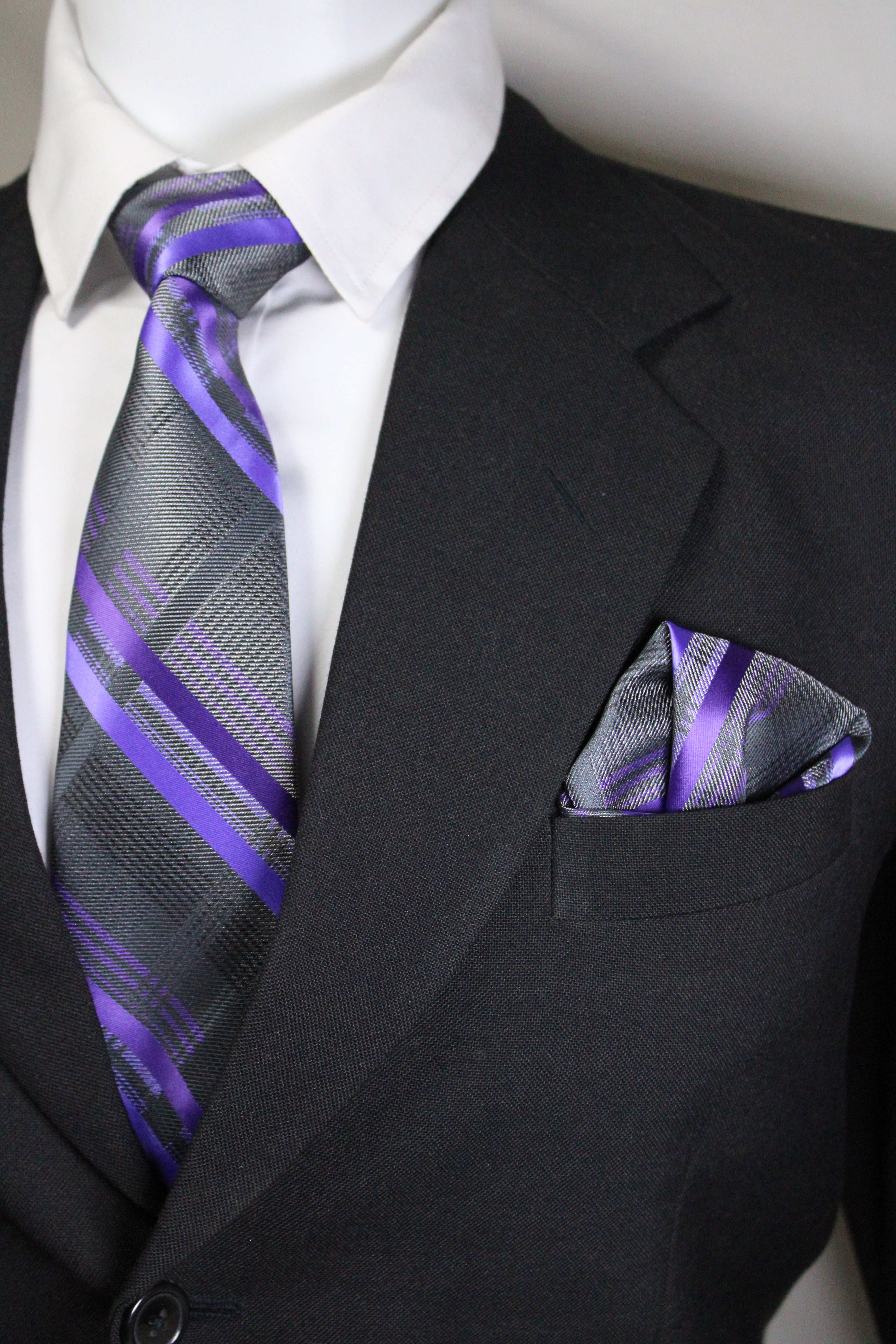 Black suit with a white shirt, purple striped tie, and matching pocket square.
