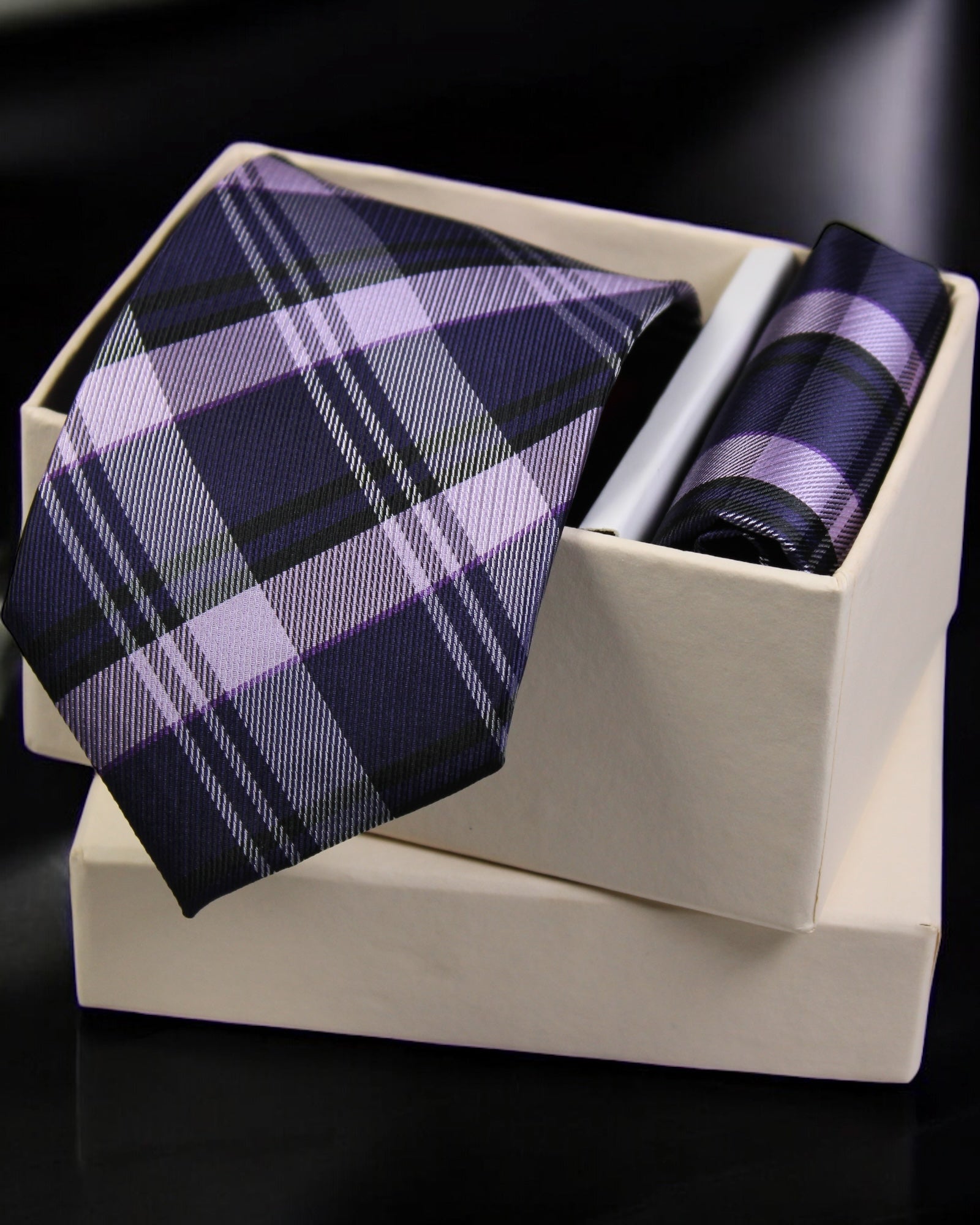 Plaid tie and pocket square set in a white box on a black background tie benon