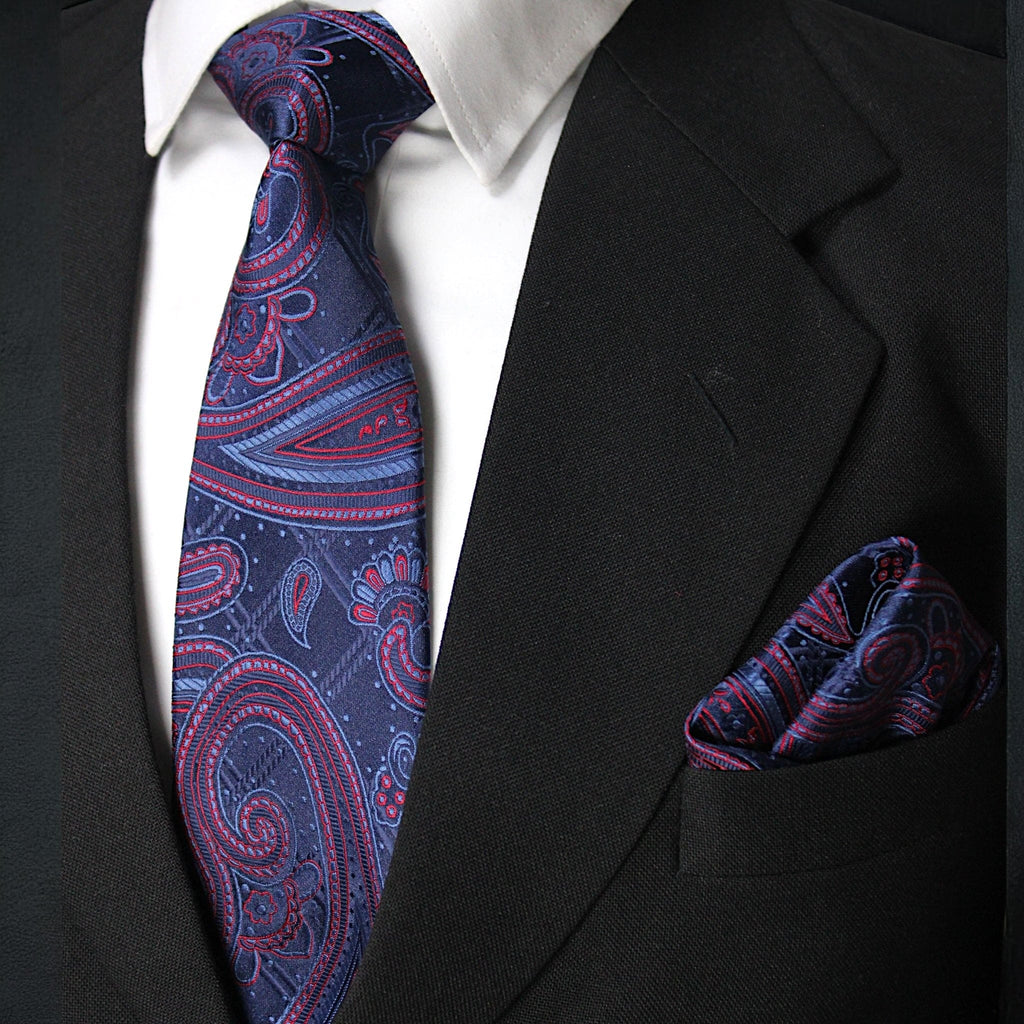 Black suit with a white shirt, blue and red paisley tie, and matching pocket square.