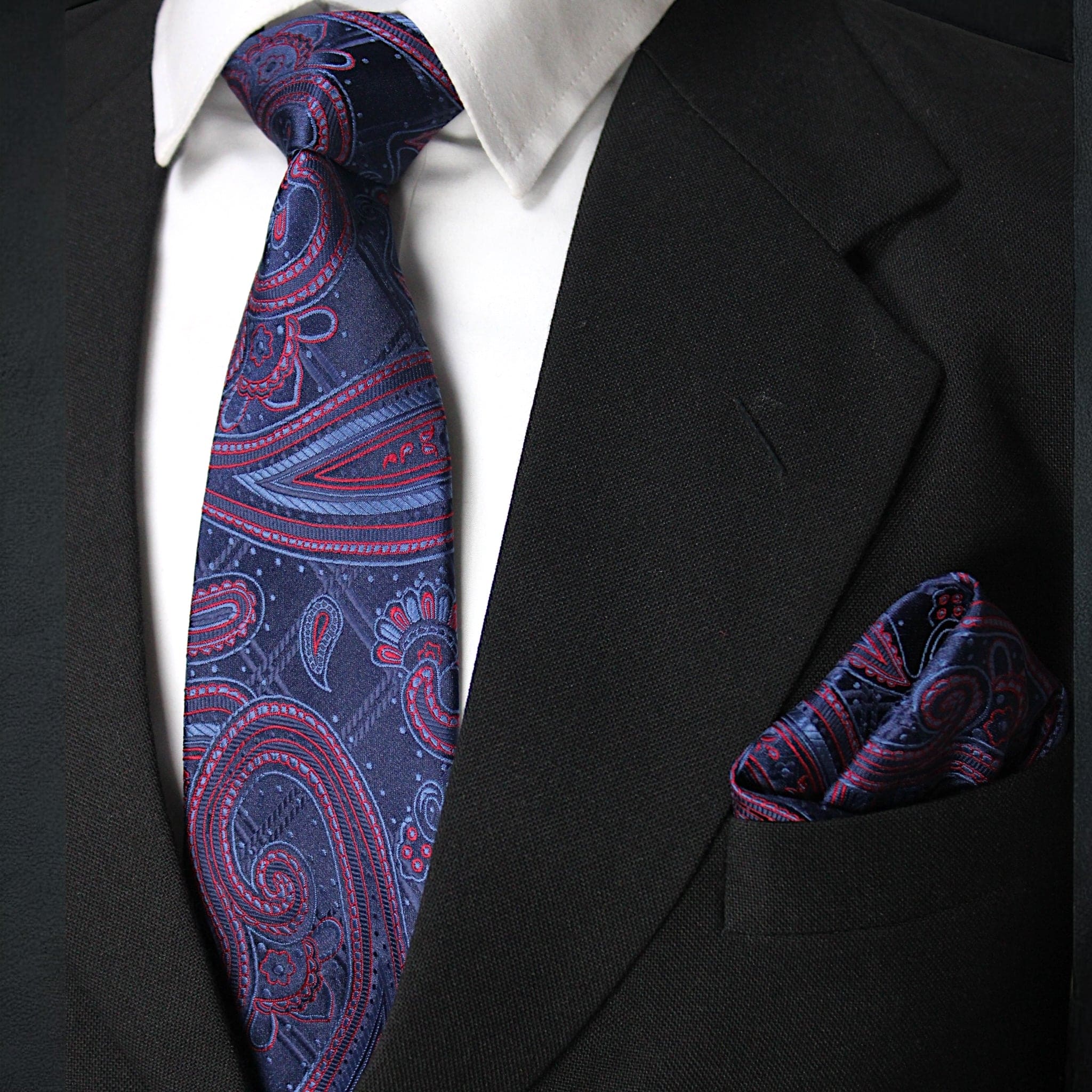 Black suit with a white shirt, blue and red paisley tie, and matching pocket square.