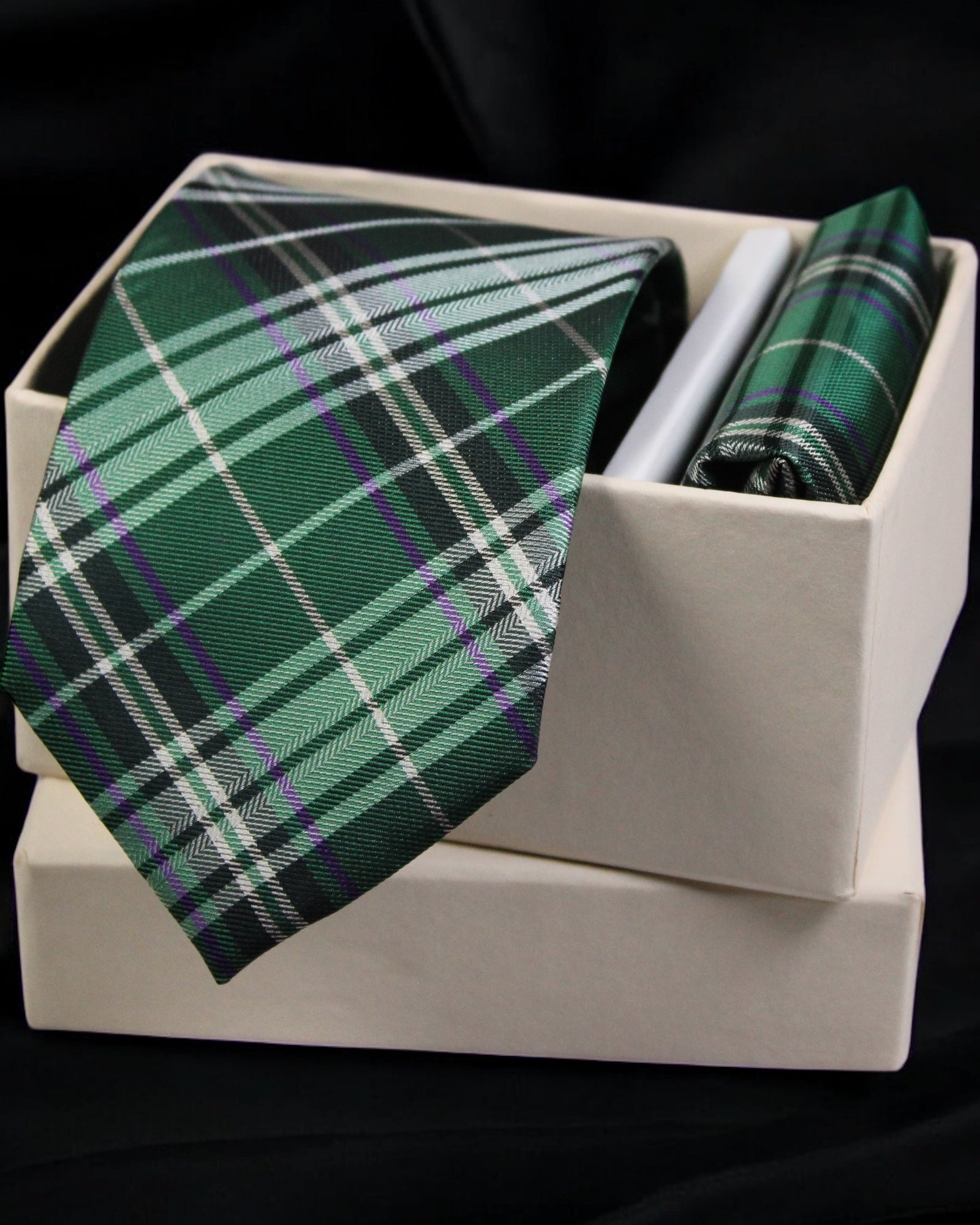 Green plaid tie and pocket square set in a white box on a black background