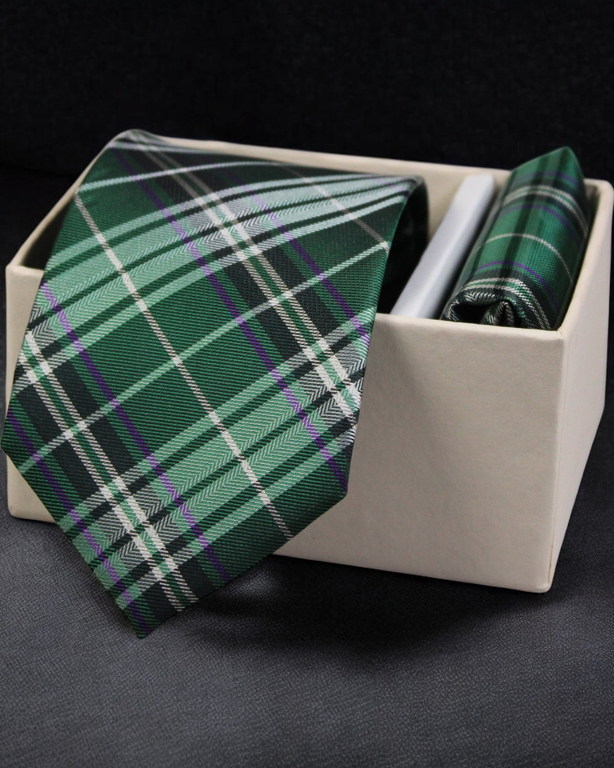Green plaid tie and matching pocket square in a white box on a dark background