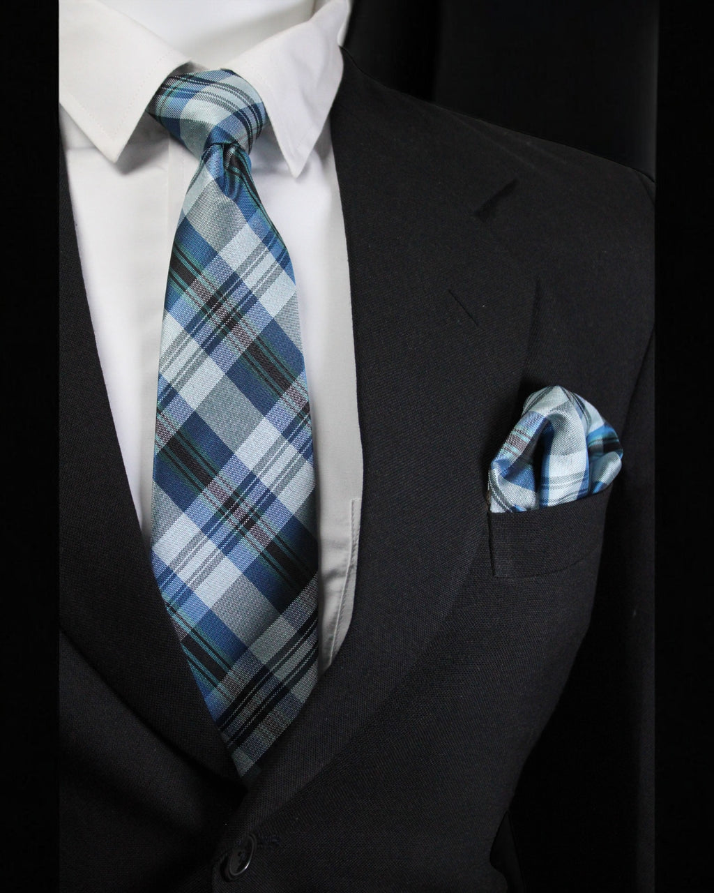 Man wearing a black suit with a white shirt, blue plaid tie, and matching pocket square Tie Benon