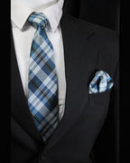Man wearing a black suit with a white shirt, blue plaid tie, and matching pocket square Tie Benon