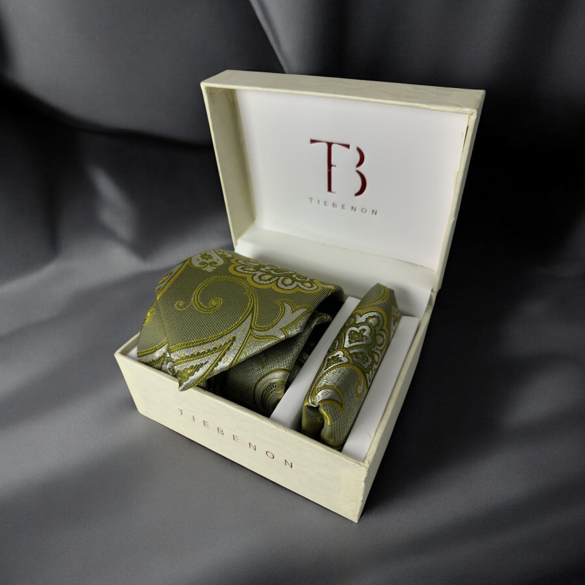 A set of pickle green paisley ties with a matching pocket square, presented in an open white box with the initial 'T' branding on the top and the brand name 'TieBenon' on the inside lid.