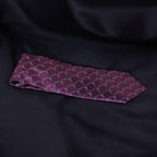 Maroon tie with a diamond pattern on a black fabric background