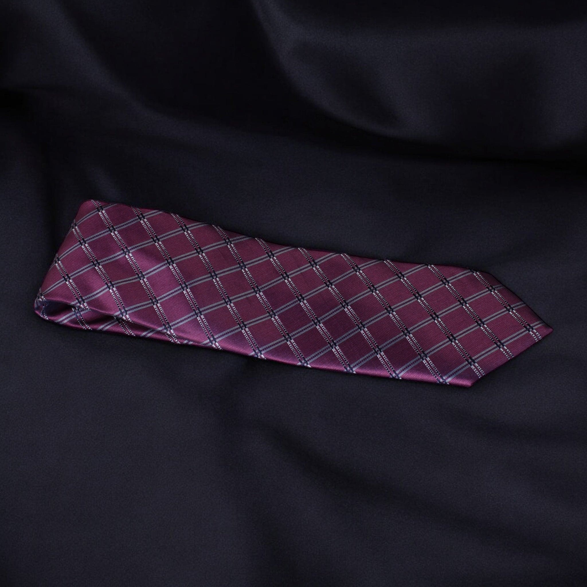 Maroon tie with a diamond pattern on a black fabric background