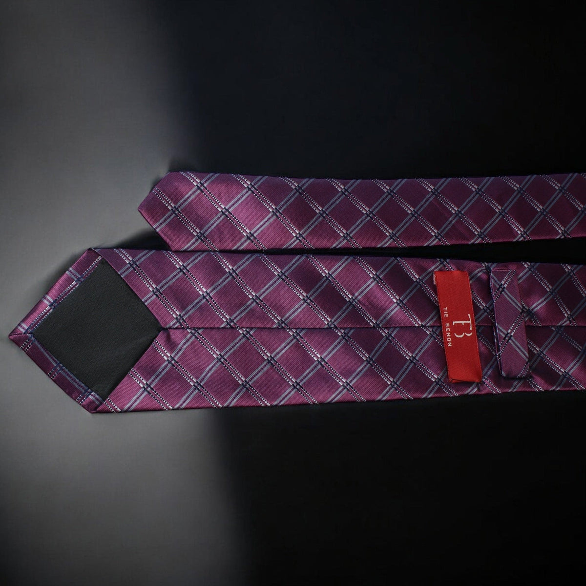 Purple patterned tie with a red tag on a dark background