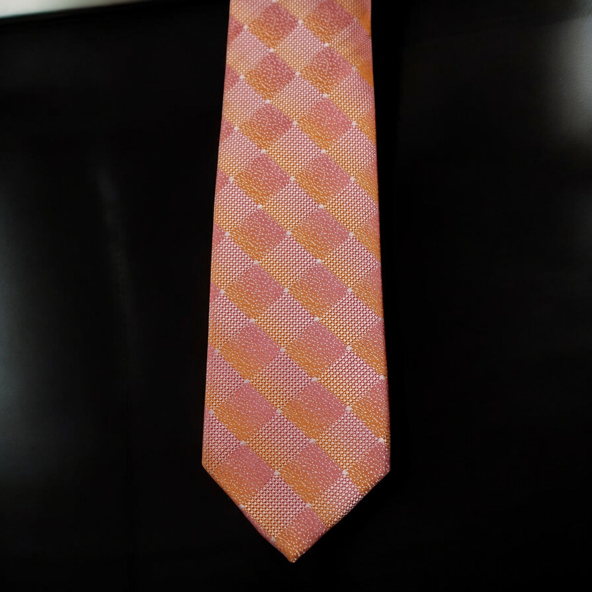 Pink and orange checkered tie on a black background