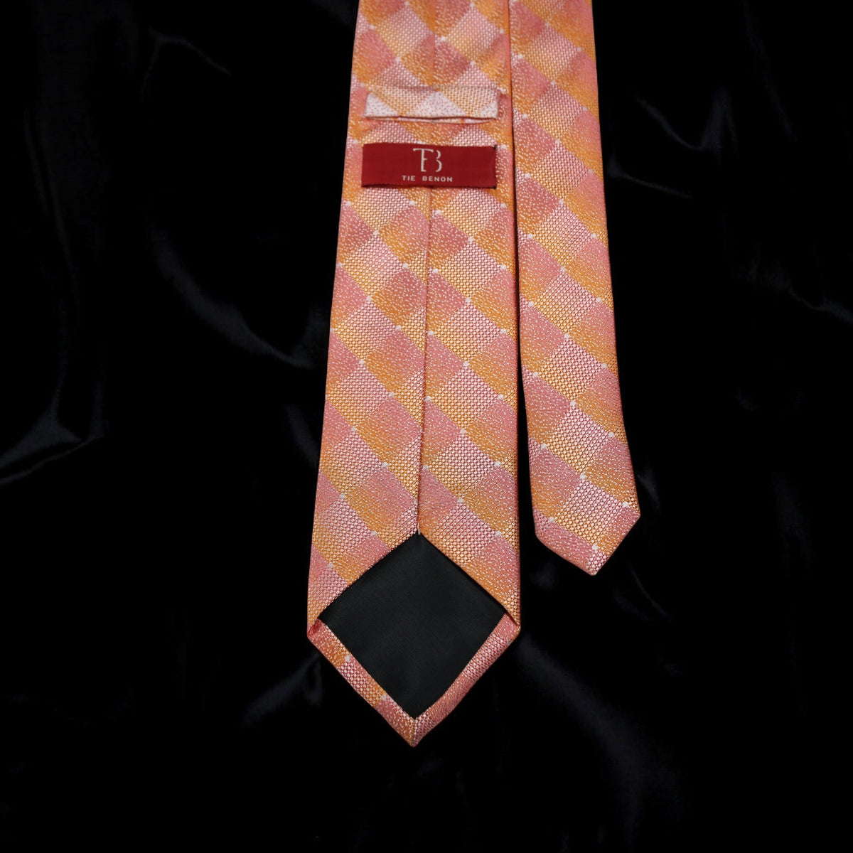 Pink checkered tie with a brand label on a black background