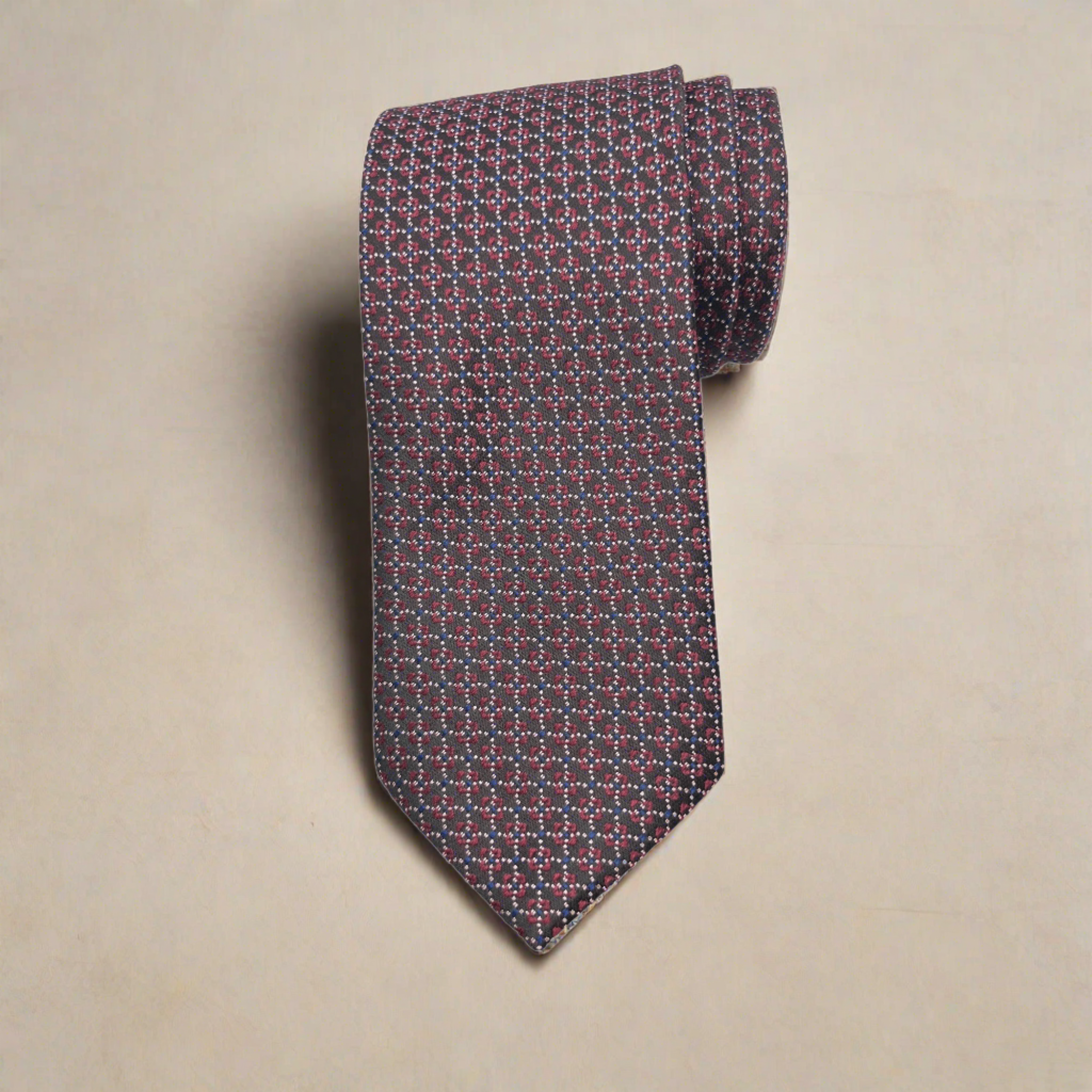 A necktie with a geometric circular pattern in burgundy and white, displayed on a plain background.