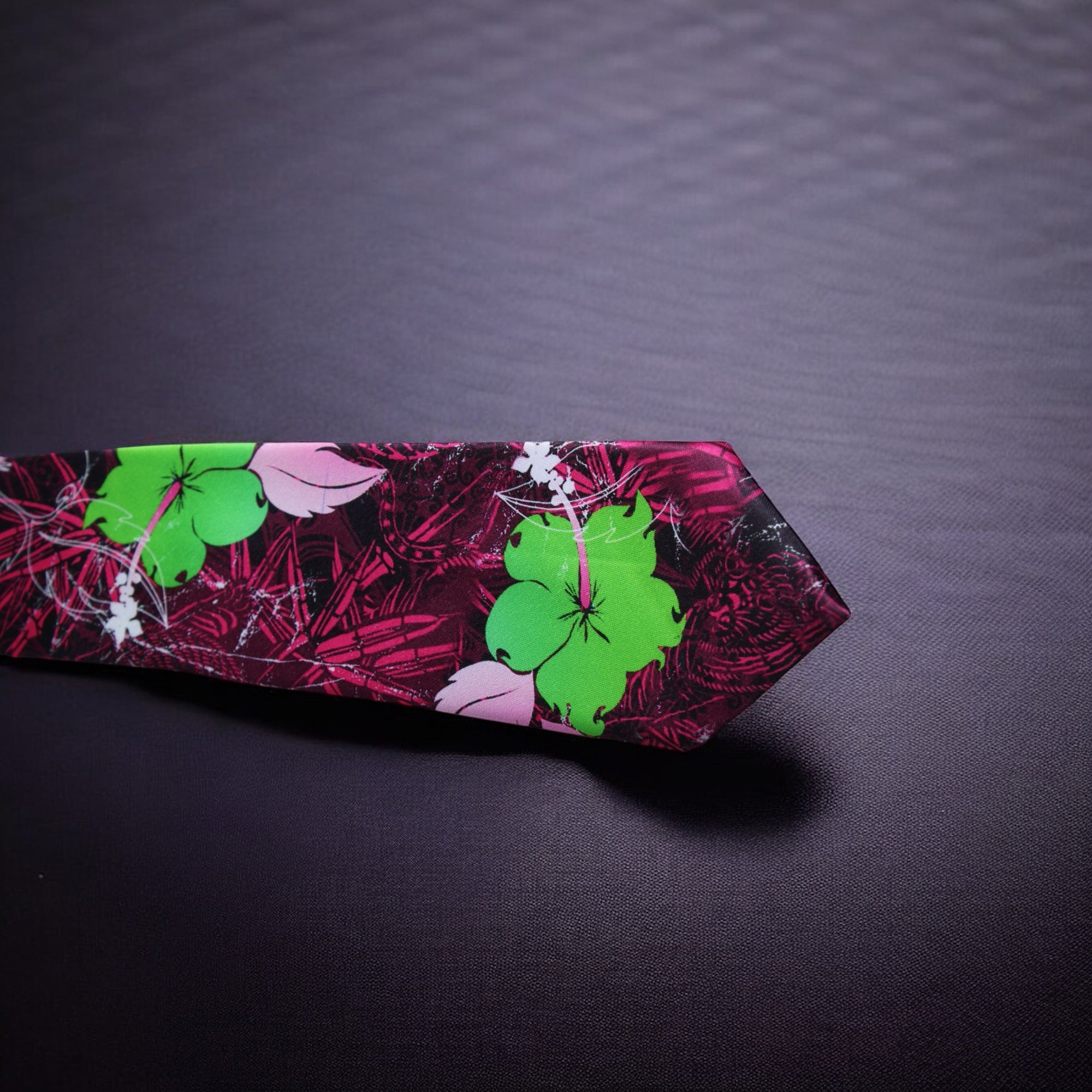 A wine-colored necktie with a floral pattern, laid out on a dark surface.